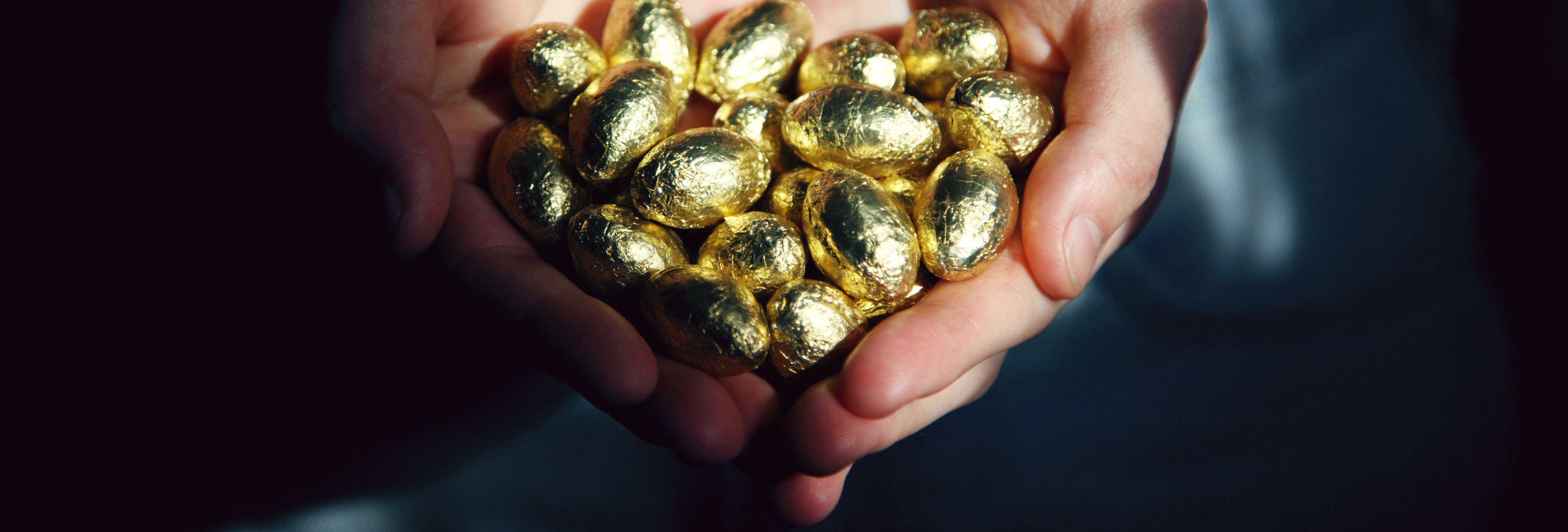 Hands holding gold eggs